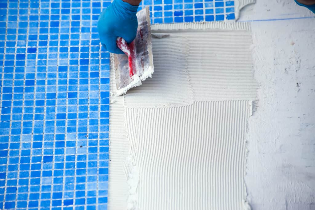 Laying bright blue tiles in the pool