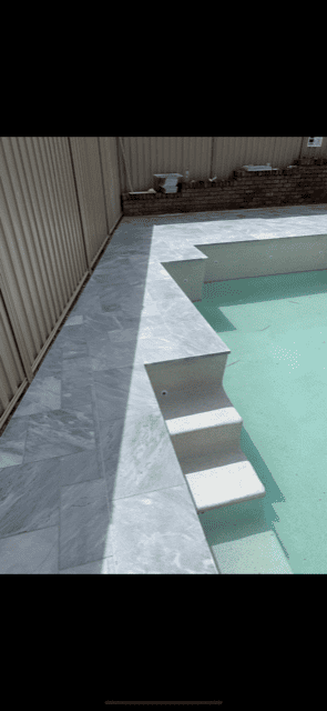 a new pool with white steps and light grey tiles