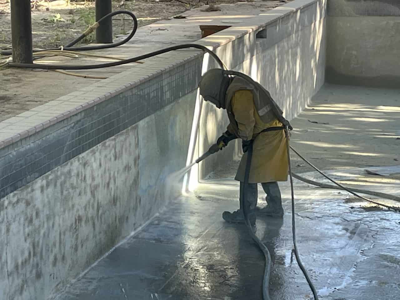 Empty pool with man hosing the sides